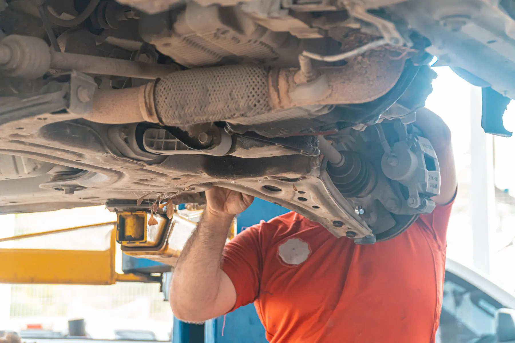 Mechanic inspecting the underside of a vehicle on a lift