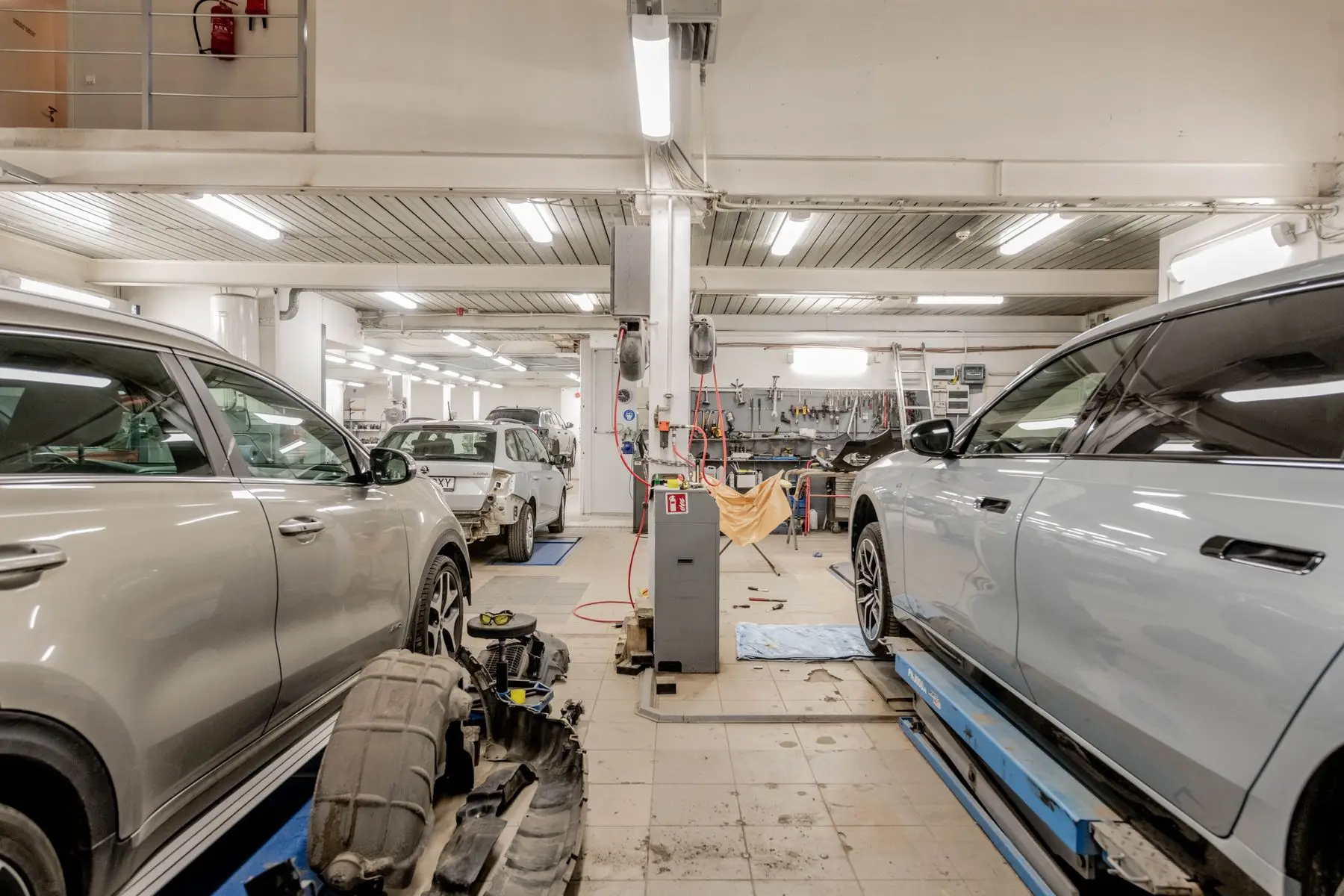 Several vehicles being serviced in a bright repair facility